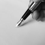 A close-up of a fountain pen writing on blank paper in black and white, capturing elegance.